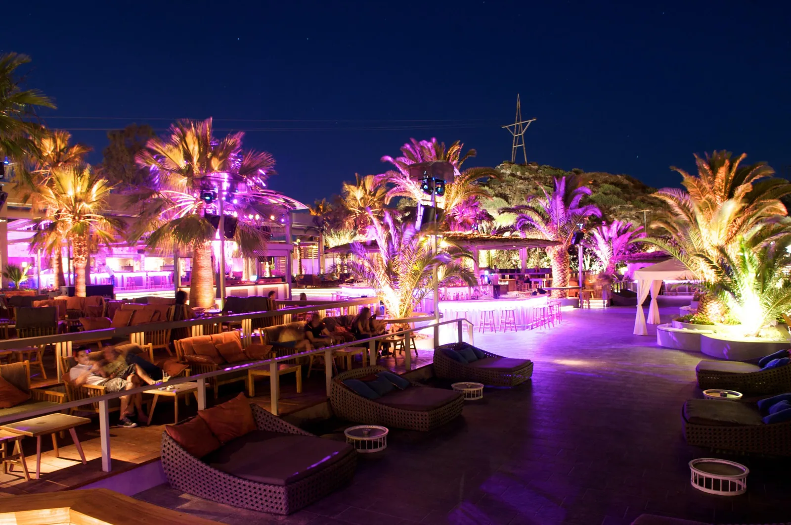 Παραθαλάσσιο beach club Mojito Bay το σούρουπο — έγχρωμος φωτισμός ανάμεσα στους φοίνικες, Βάρκιζα